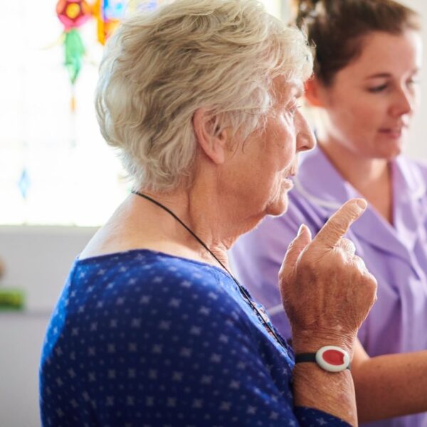 home carer showing senior woman her alarm panel